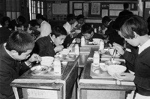 09先割れスプーンを使用した学校給食・上遠野中学校(昭和45年10月、いわき市撮影)：食器に顔を近づけてしまって食事姿勢が悪くなっているようにも見えます…