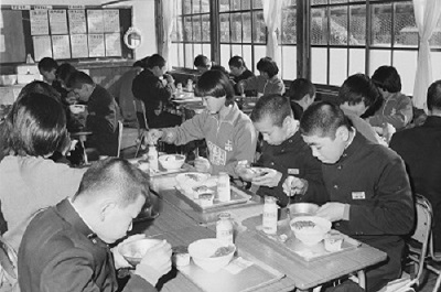 05導入実験期間中の米飯給食・上遠野中学校(昭和51年2月、いわき市撮影)：みんな納豆ごはんにしているようです。あ！中央の子だけプリンが2つ！