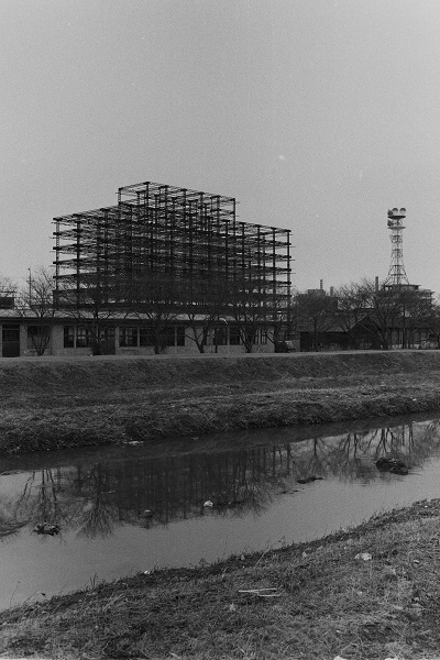 02_04市役所本庁舎建設中を新川右岸から見る(昭和47年2月、いわき市撮影)：骨組みができ上がったころでしょうか。全貌が見えてきました