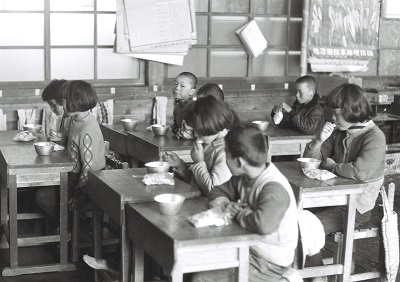 給食風景2・小玉小学校(昭和30年代、国府田英二氏提供)：アルミのおわんで脱脂粉乳を飲んでいるようです