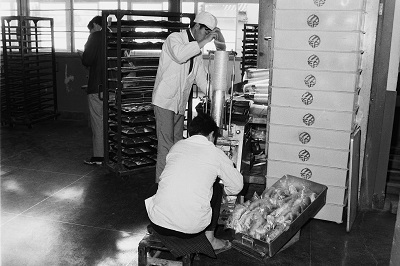 勿来給食センターパン工場での給食パンの製造・パック詰め(昭和47年1月、いわき市撮影)：大きなコッペパンをひとつひとつ手作業で詰めていたようです