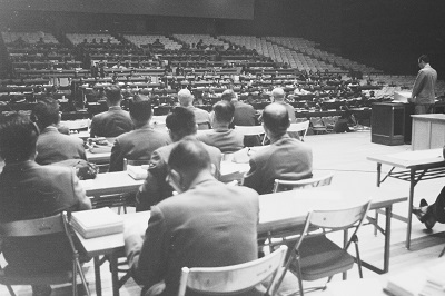 02_マンモス市議会の理事者席・6月定例会（昭和42年7月）：理事者（説明者として出席する市の担当者）はステージ上に並びました