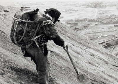 石炭を拾い集め、スコップを支えにズリ山を下りる女性(昭30代半ば、米川義克氏撮影)