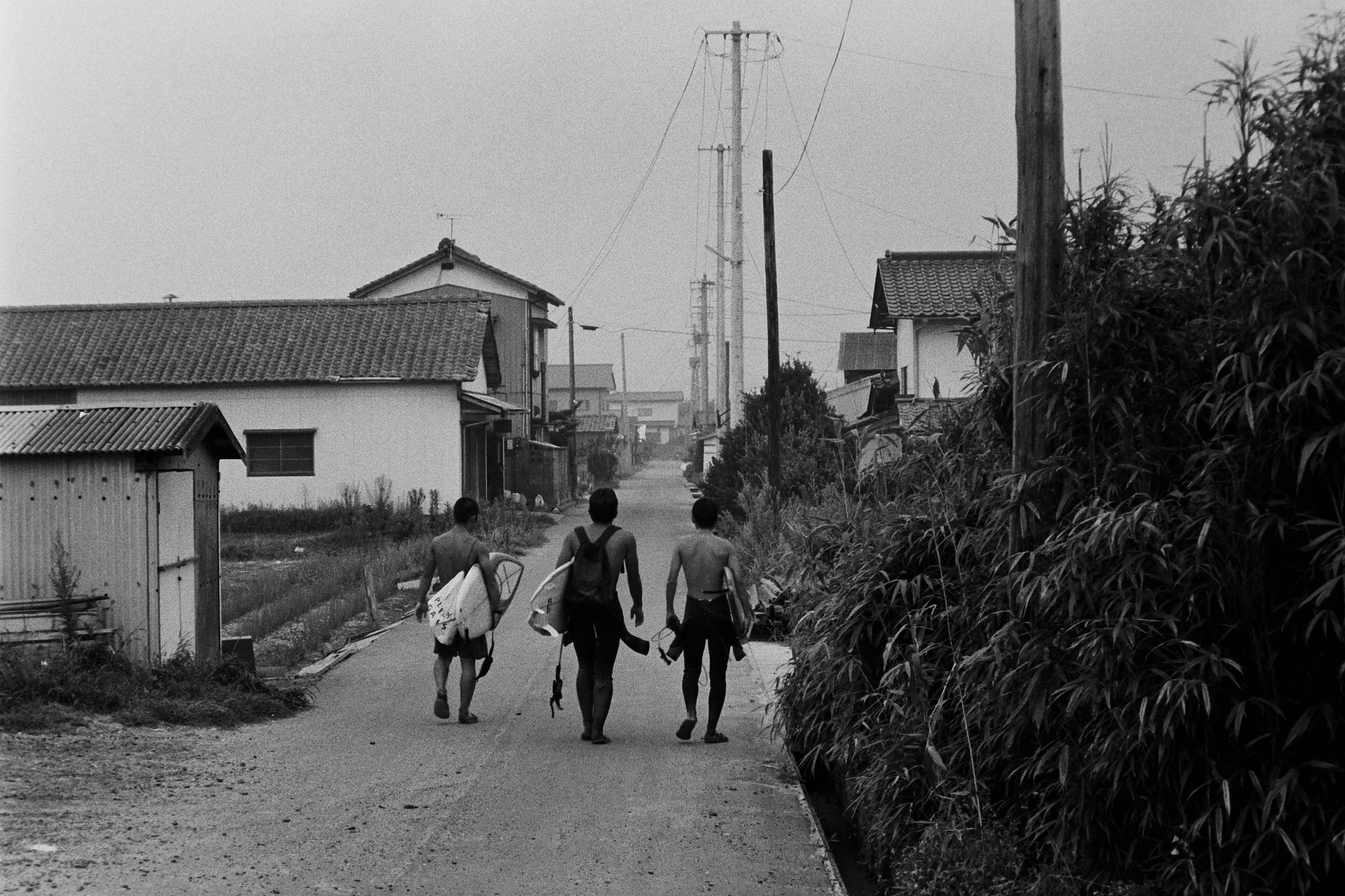 須賀集落内の市道を行くサーファー