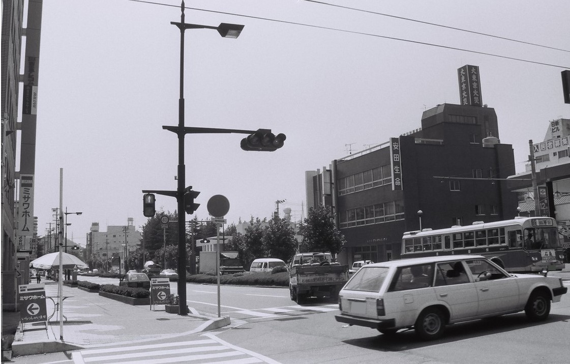 ■写真1-2　駅前広場となる予定だった空地は小太郎公園（写真中央の樹木地）として整備　〔昭和63年(1988)8月　いわき市撮影〕