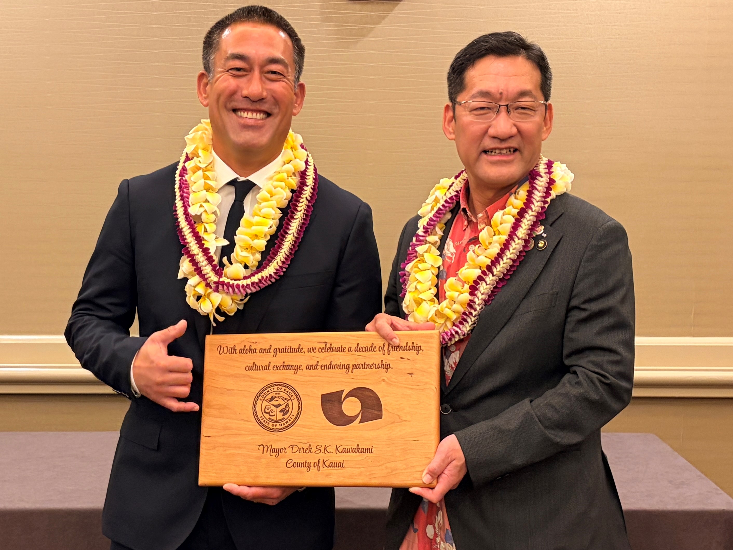 カワカミ郡長から贈呈された木彫りの記念の盾を持つカワカミ郡長と内田市長