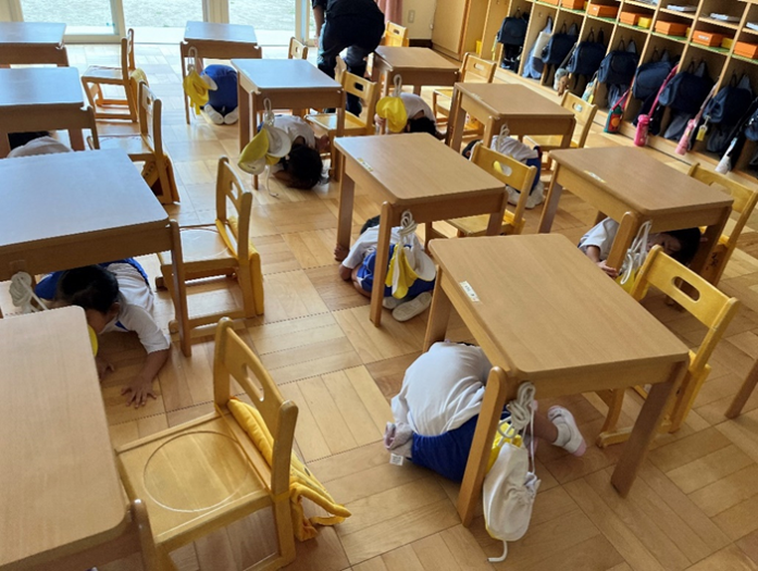 机の下に身を隠す園児たちの様子