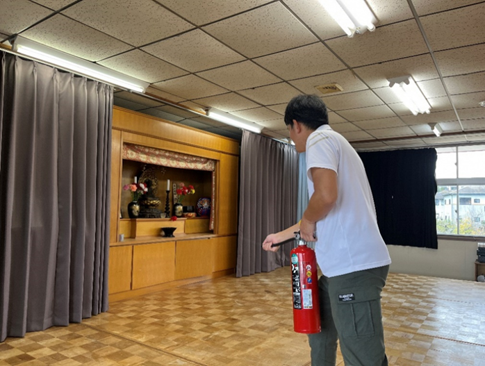お遊戯室で消火訓練をする先生の様子